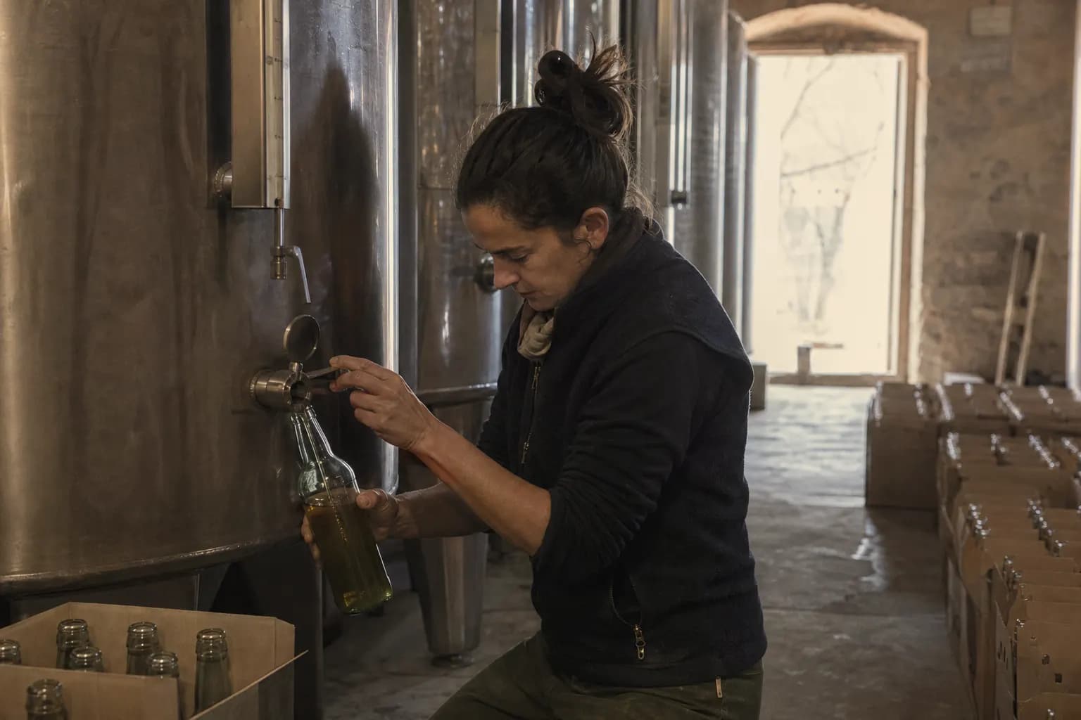 Nerea Bel bottles olive oil from a steel tank at the mill