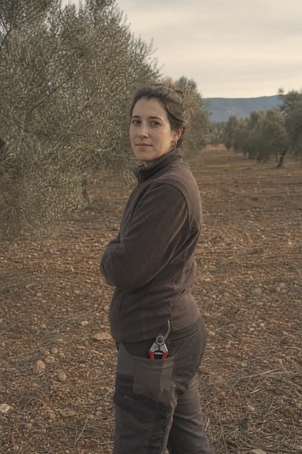 Nerea Bel, aged 29, standing among the olive trees on her farm in Calaceite