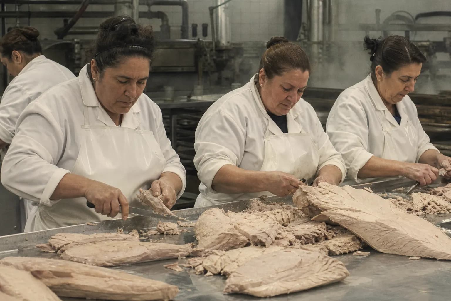 Workers clean the cooked tuna loins by hand in the cannery