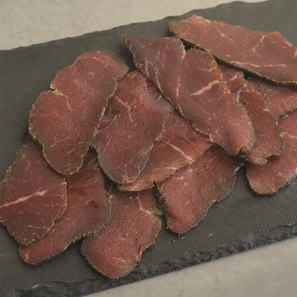 Thin slices of cecina with a drizzle of oil on a slate plate