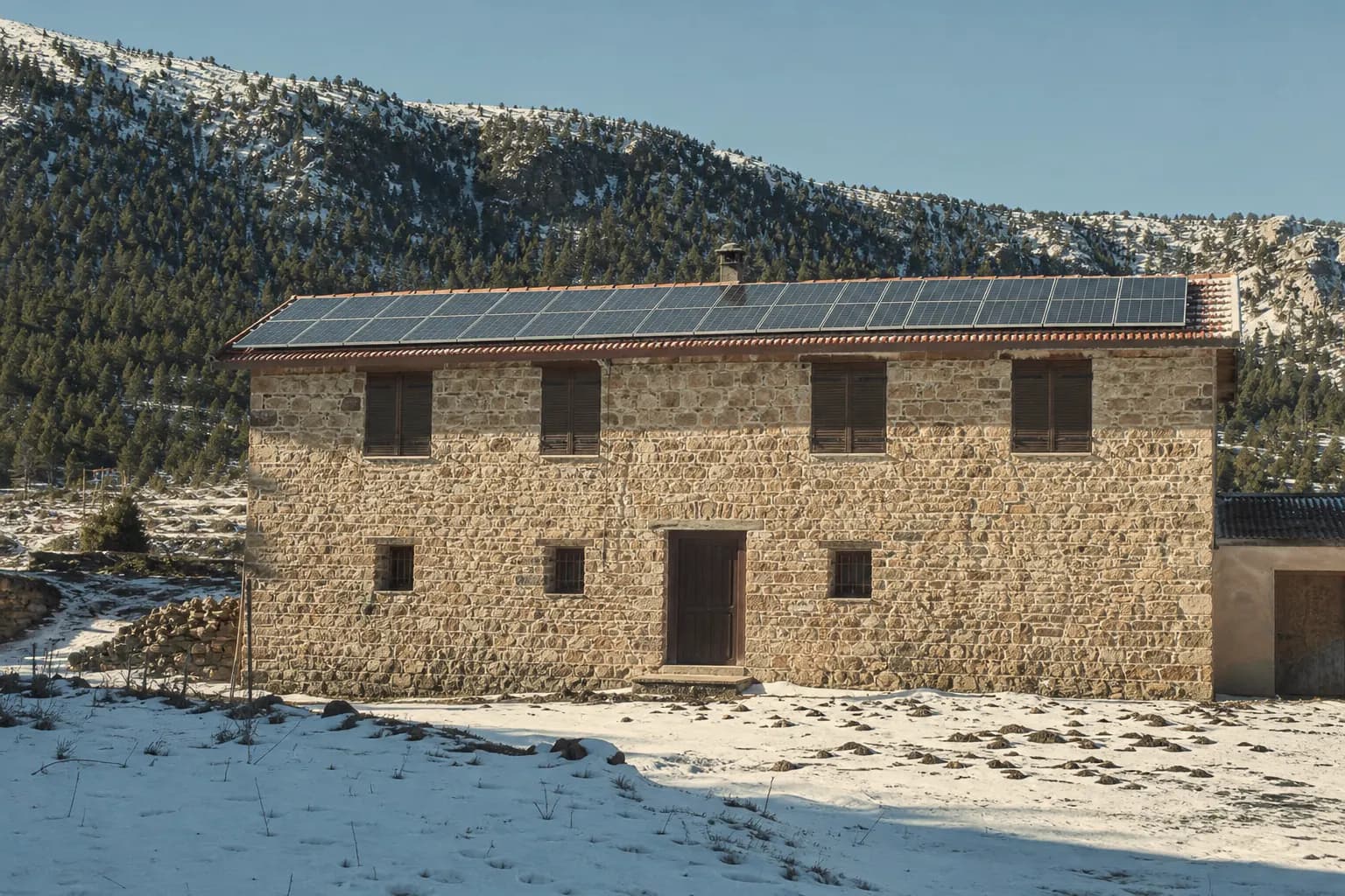 Solar panels on the Valdelinares drying house roof with snow and pine forest