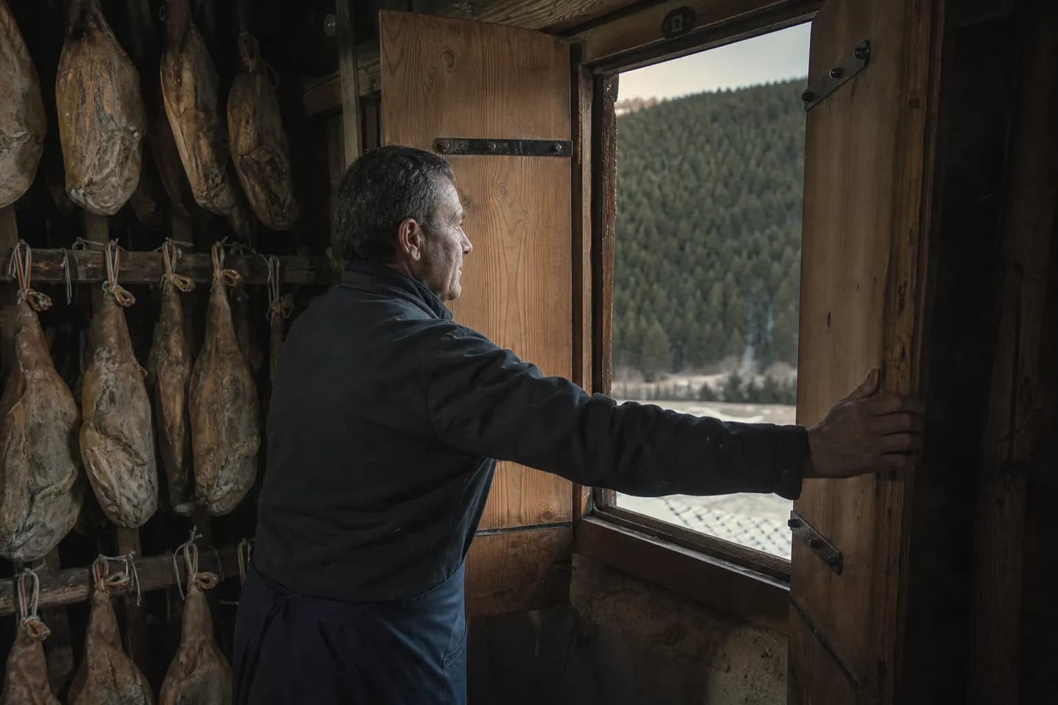 Javi Monfort opens the drying house shutters to the mountain air at dawn