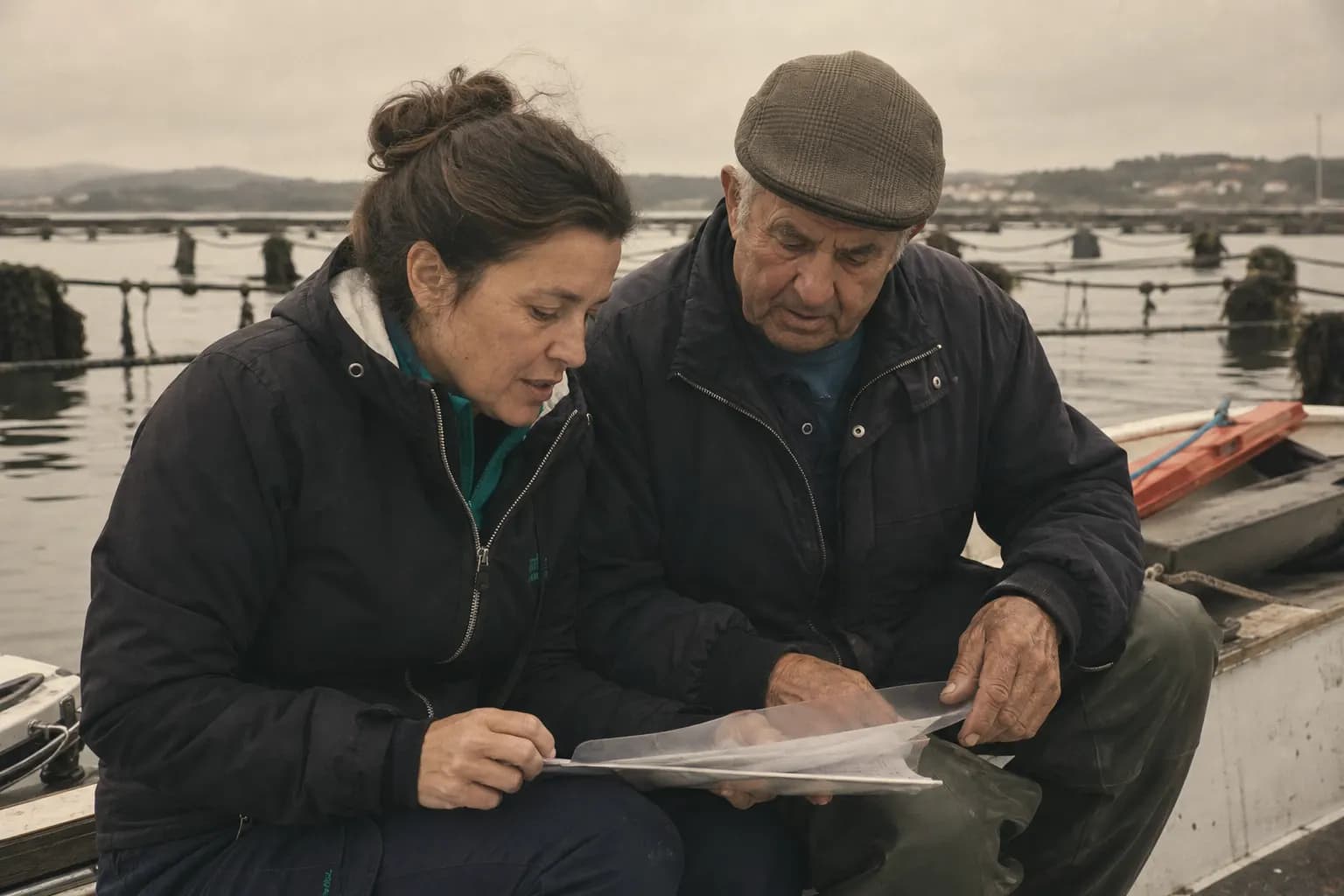 Xiana Otero and her father go through papers sitting on the boat