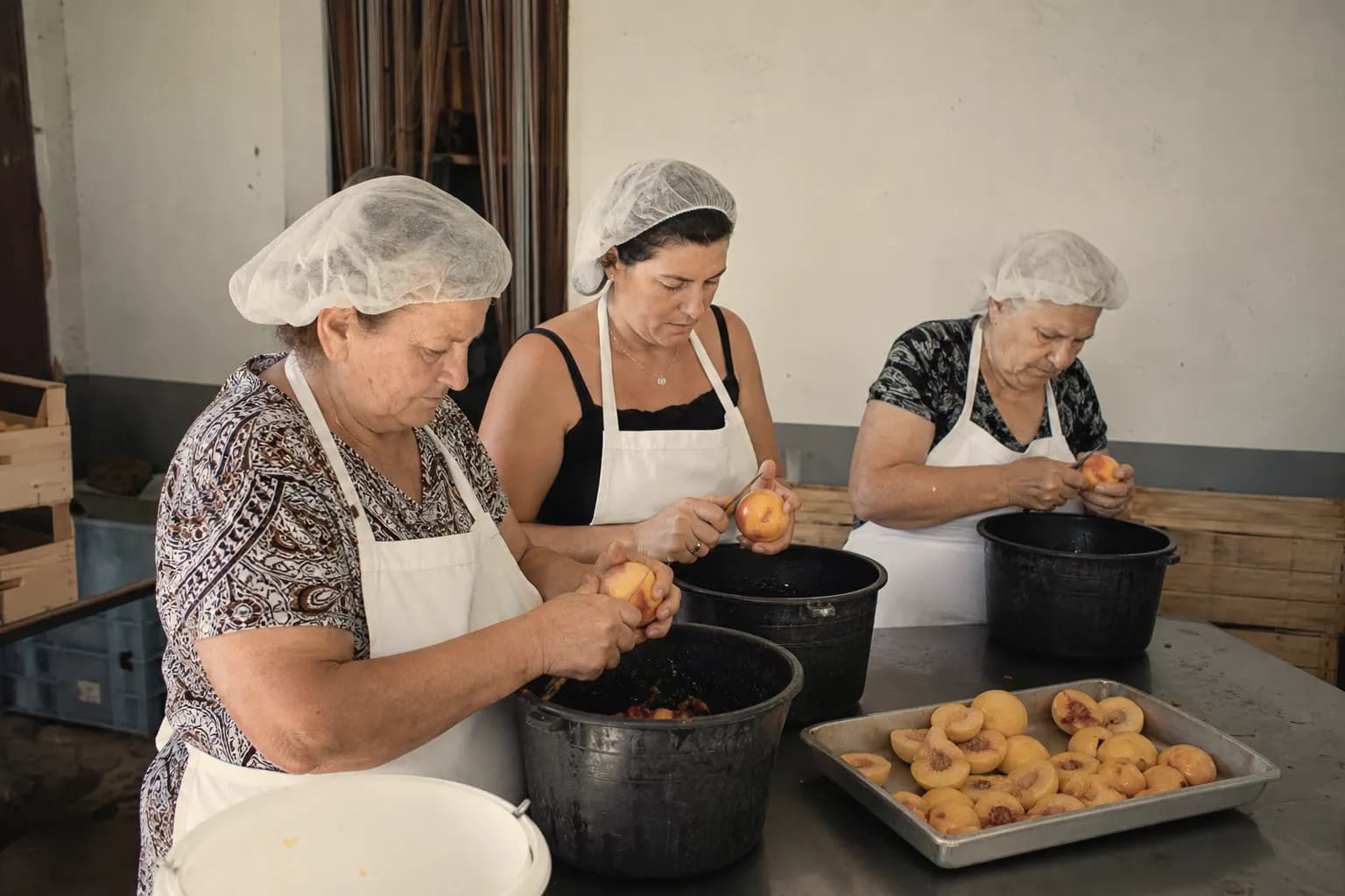 Carmen Nogués and two neighbours peel and stone peaches by hand