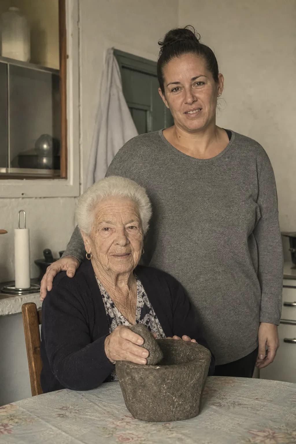 Candelaria Pérez with her stone mortar and her granddaughter Yurena in Puntagorda