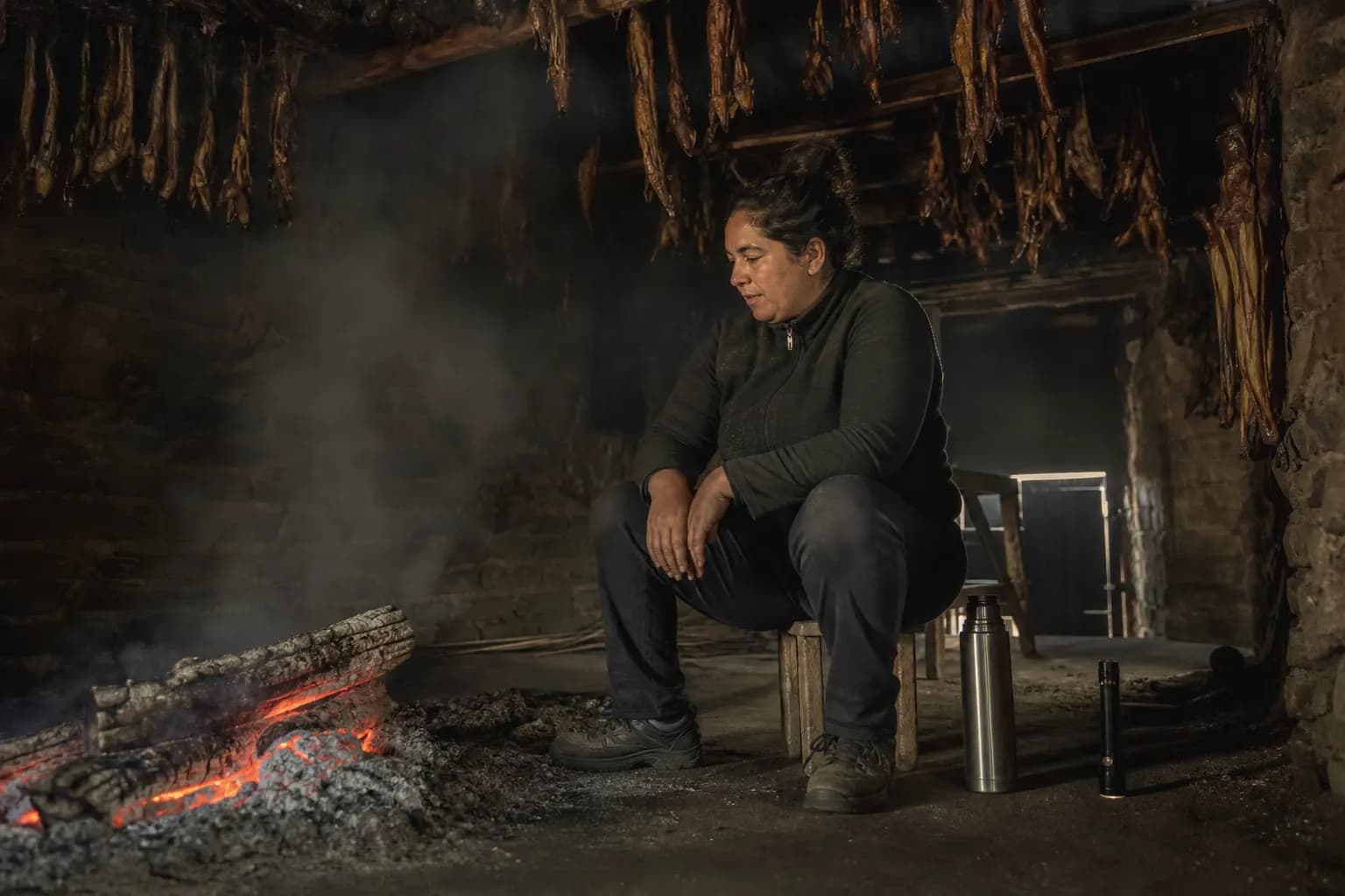 Marisa Tovar watches the oak fire at night in the smoking house