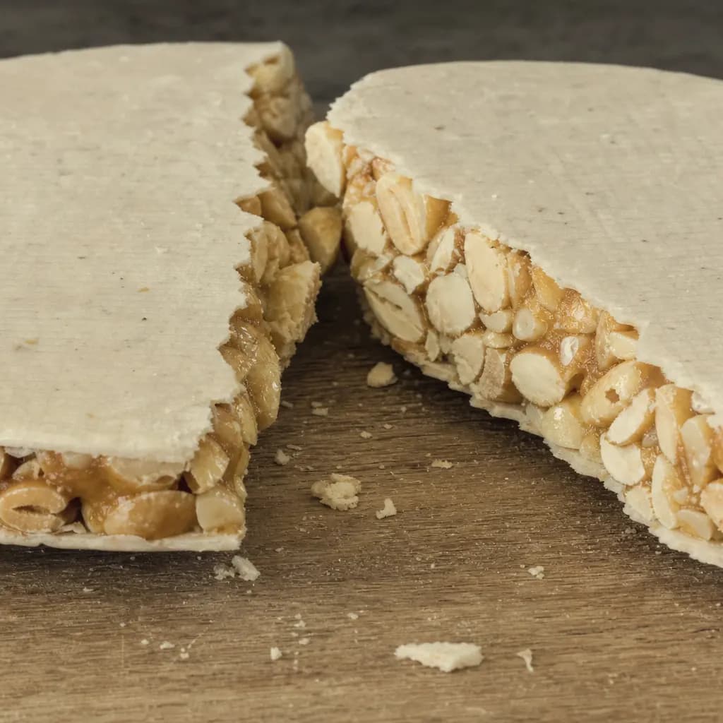 Torró broken in two showing whole almonds bound by honey between wafers