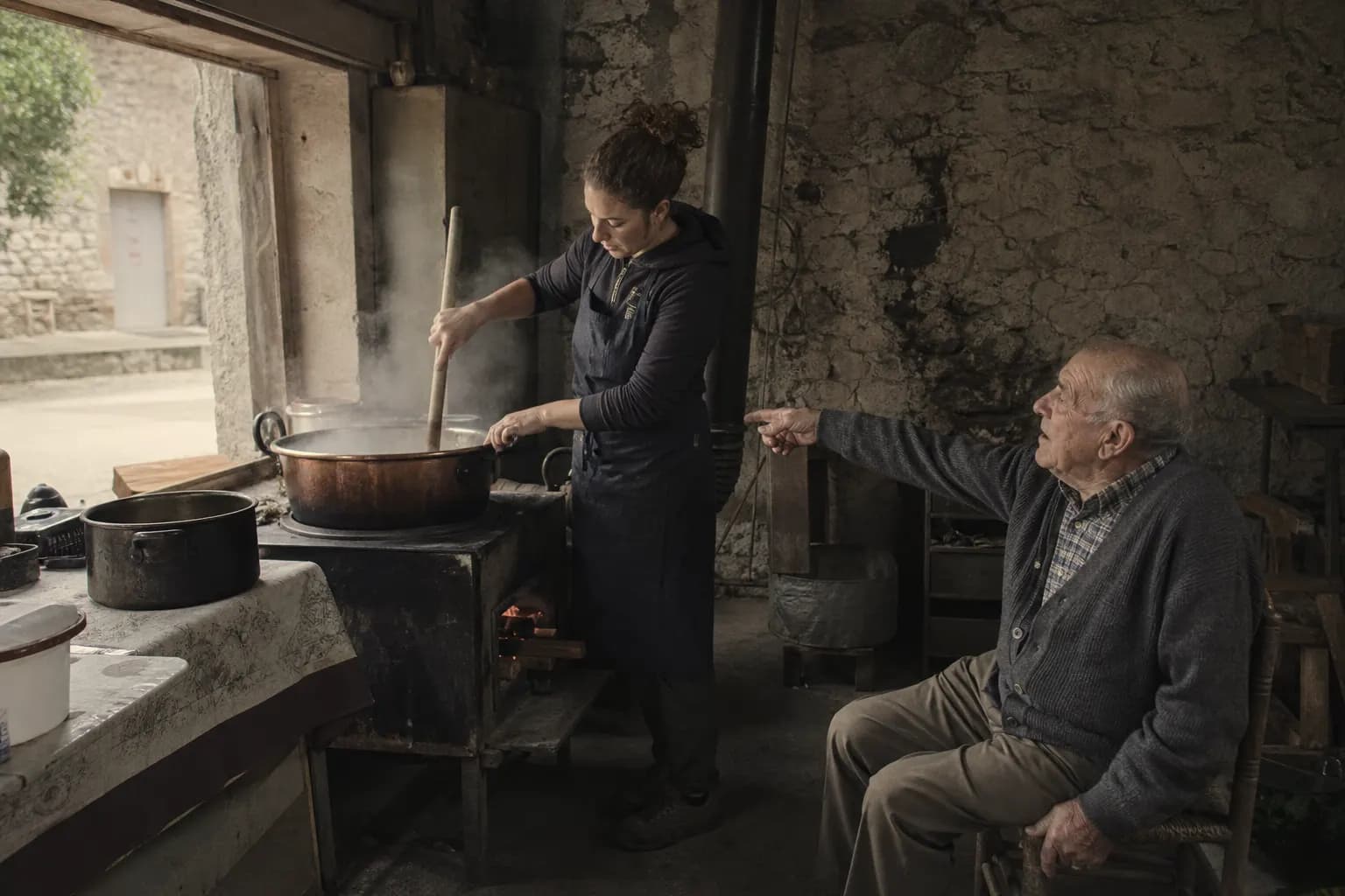 Clara Solé stirs the honey while her grandfather Ramon directs her from his chair