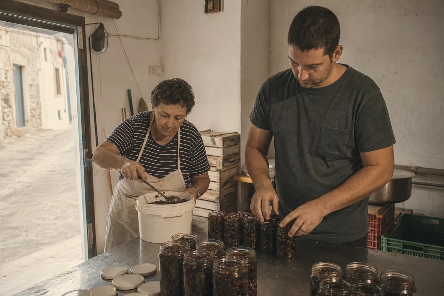 Mother and son work side by side filling jars in a small family workshop