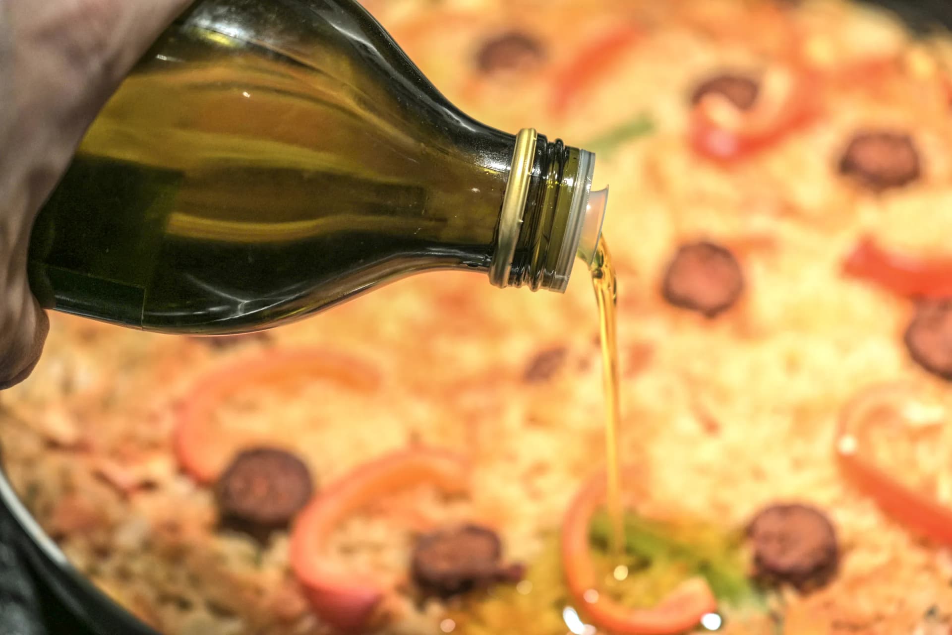 Oil pouring from the bottle over a freshly made dish