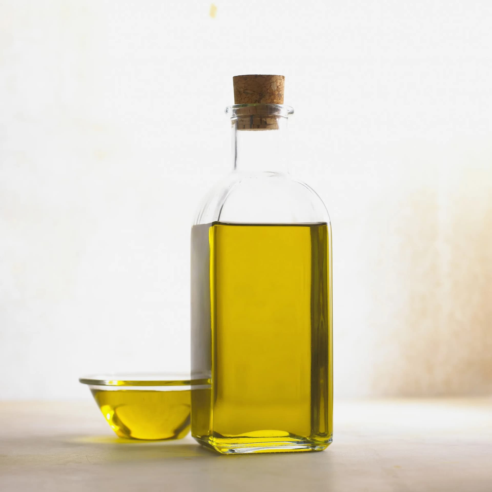 A glass bottle with a cork stopper full of olive oil