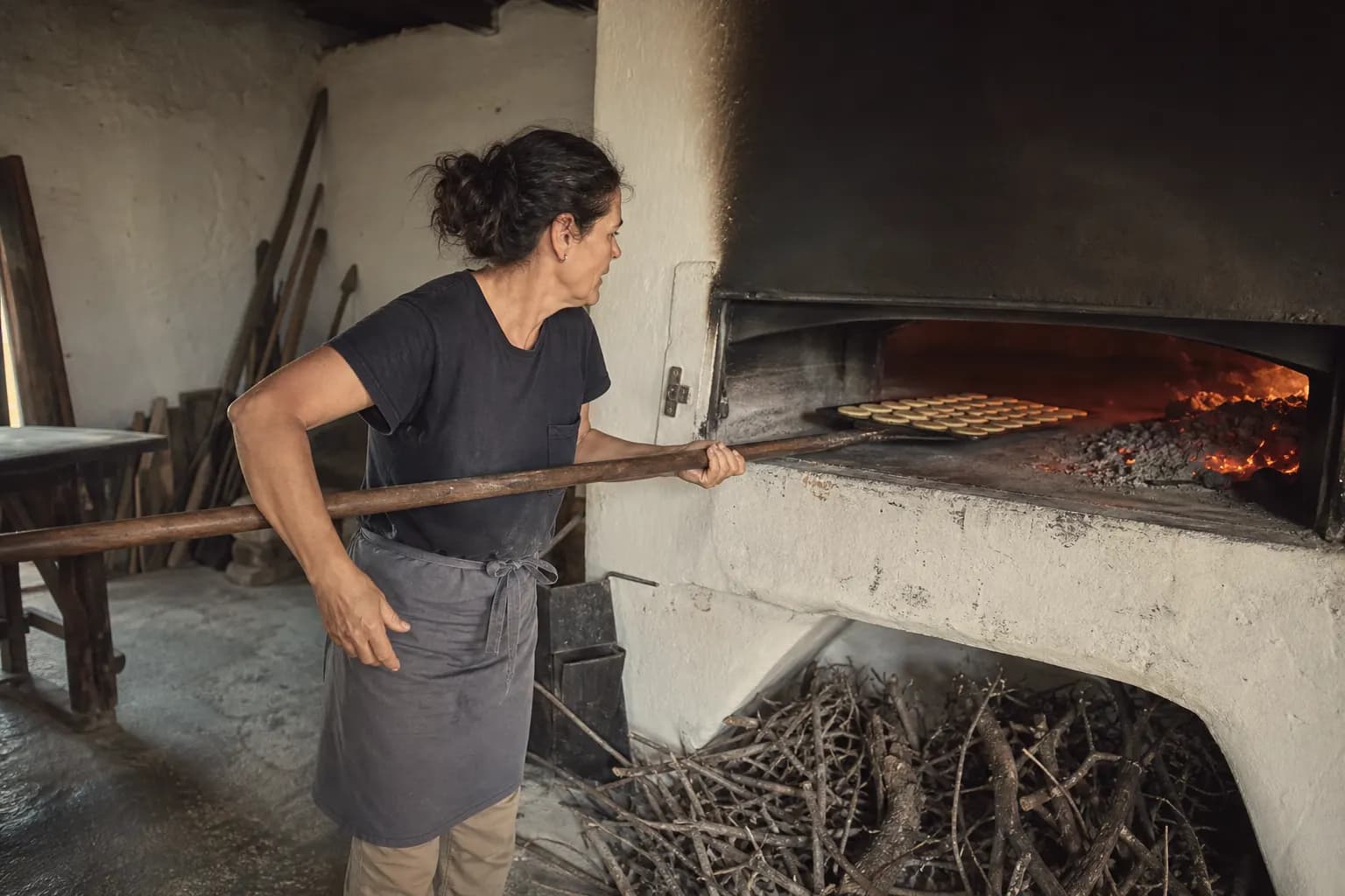 Aina Ramis slides the crackers into the wood oven on a long peel