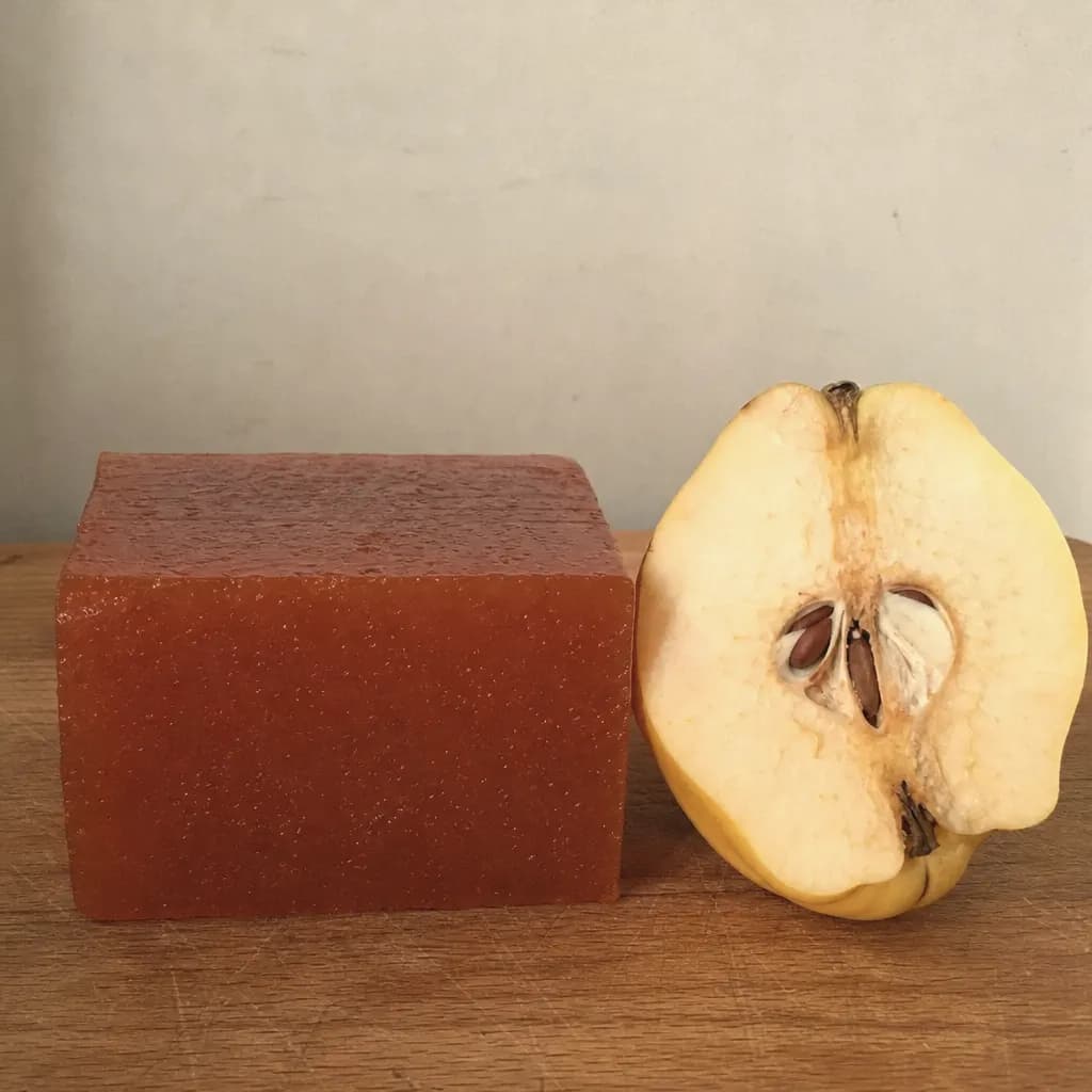 Cut block of firm quince paste beside a halved quince