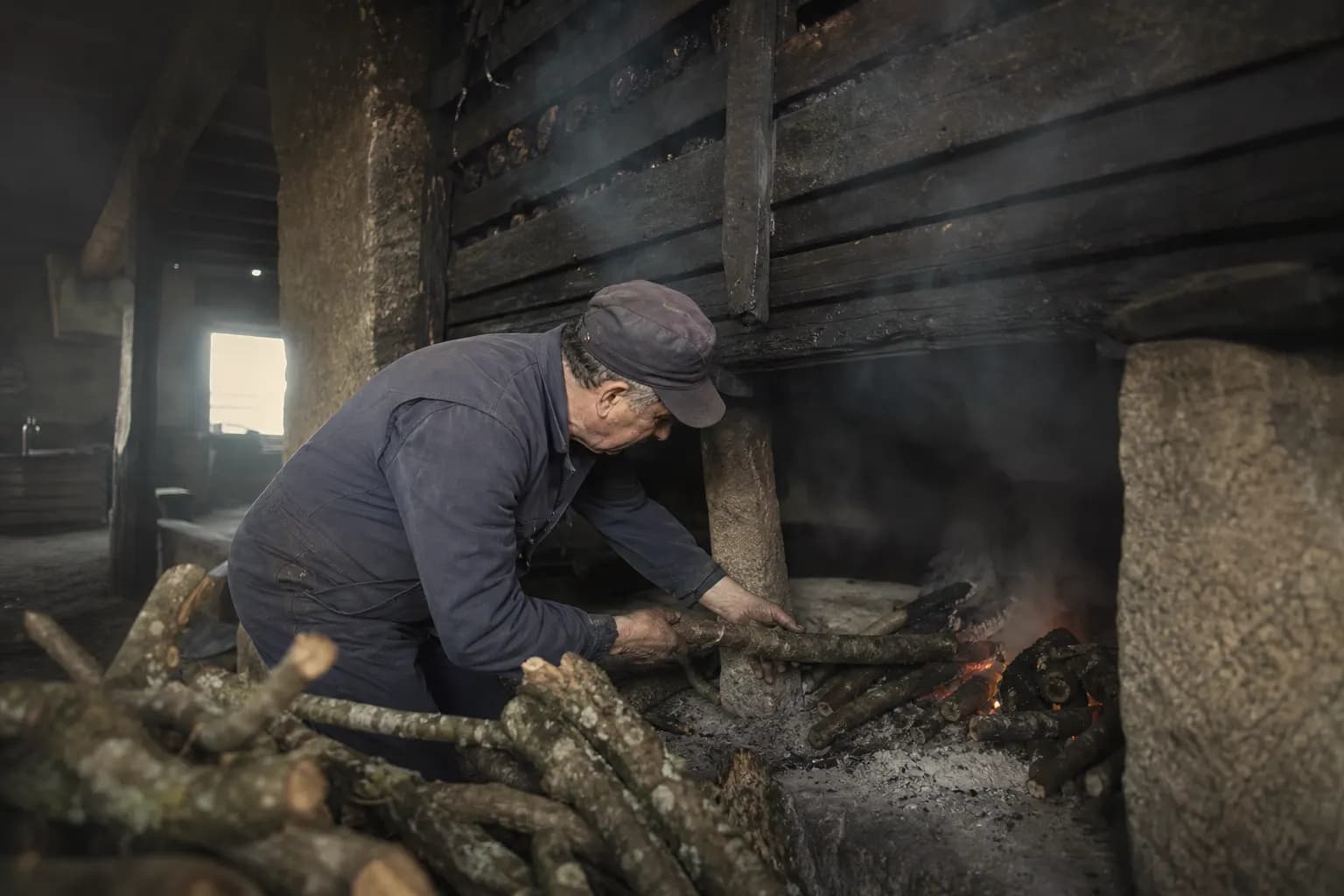 Celestino Tovar feeds the oak fire beneath the peppers