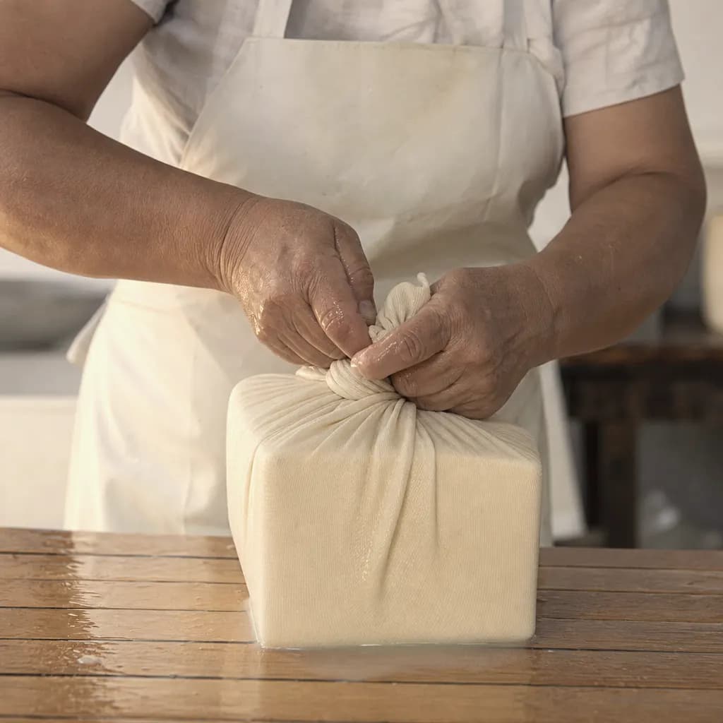Joana Pons's hands press the cloth around the fresh curd