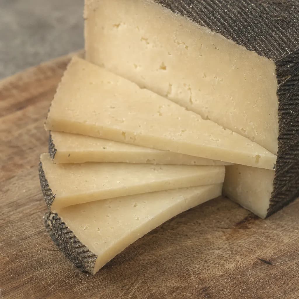 Wedge of cured manchego cut into triangles on a board