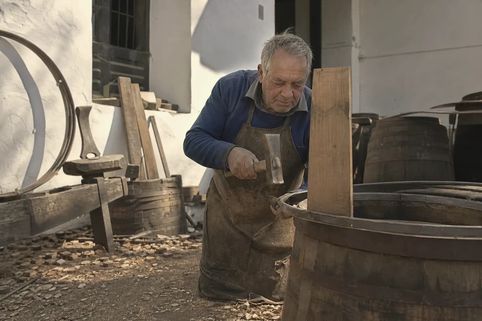 A cooper repairs an old cask in the bodega yard in Sanlúcar